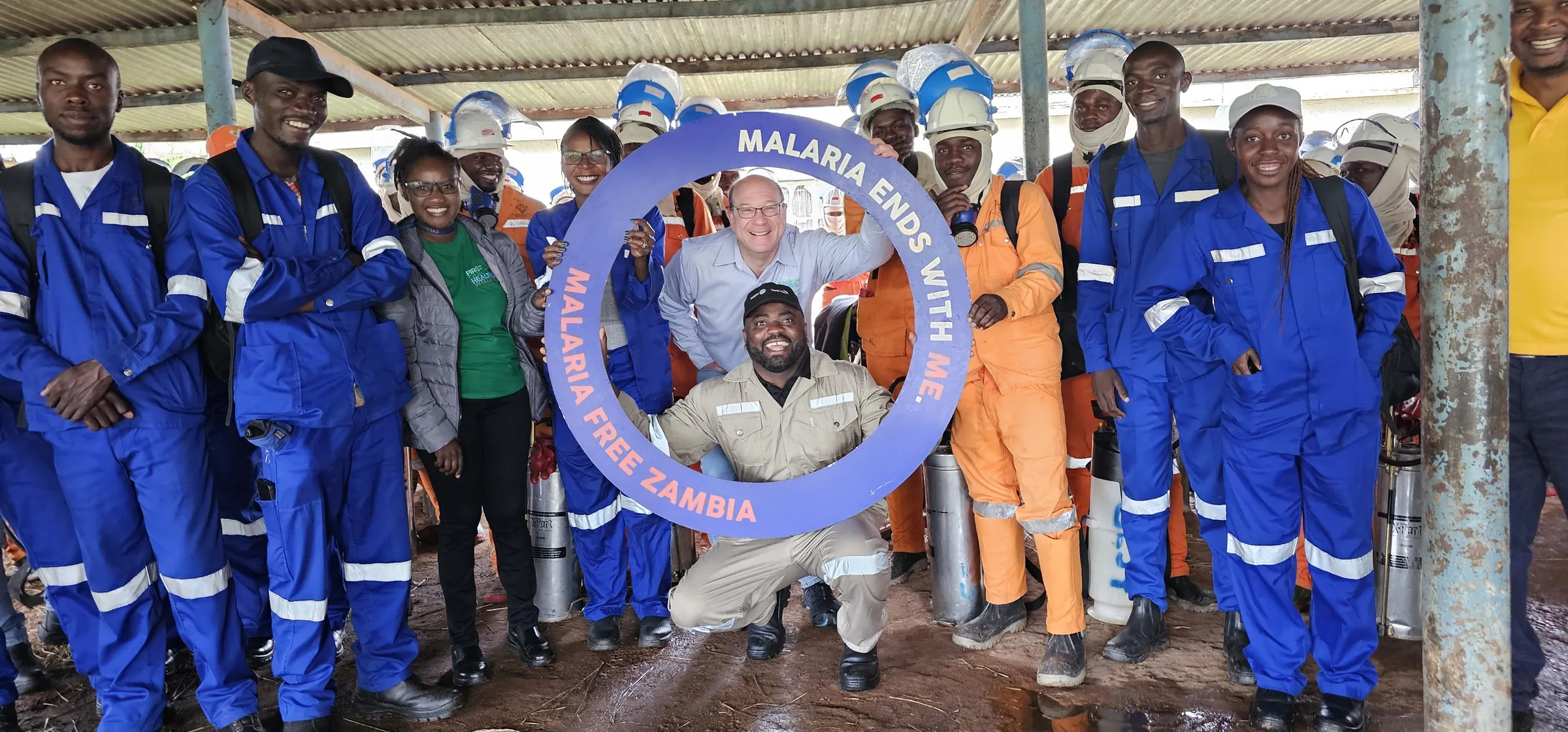 Workers holding a Malaria Free Zambia campaign banner